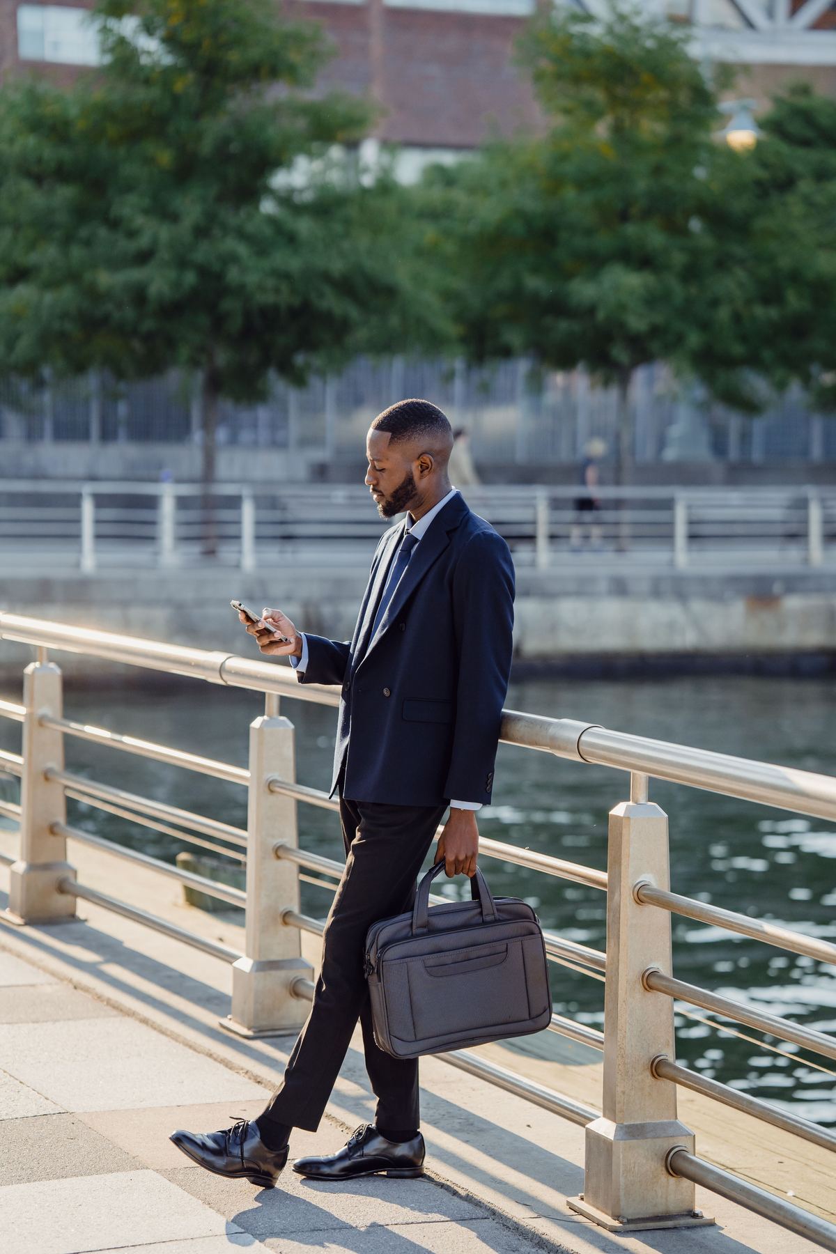 Man in pak die zijn telefoon bekijkt aan het water